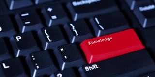 男性手指按下电脑键盘上红色的“知识”按钮