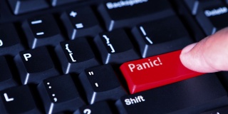 男性的手按下了电脑键盘上的红色按钮，上面写着恐慌