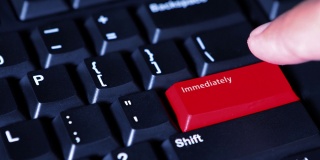 男性手按下电脑键盘上的红色“立即”按钮