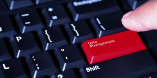 男性用手按下电脑键盘上的红色按钮，按钮上的文字是“数据管理”