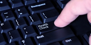 男性手按下电脑键盘上的“健康检查”按钮