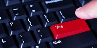 在电脑键盘上，人手按下红色的“Yes”按钮
