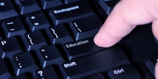 一个男性手指按下计算机键盘上的“教育”按钮的微距视频片段