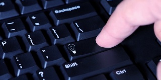 一个男性手指按下电脑键盘上的灯泡按钮的视频片段