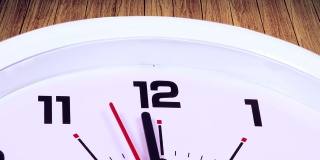 一个12点钟带着一个箭头的挂钟的视频片段，用木制背景拍摄