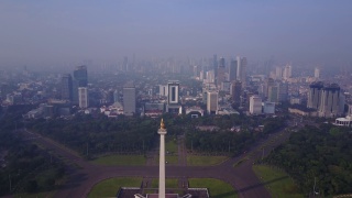 印尼雅加达，国家纪念碑上的摩天大楼在雾蒙蒙的早晨鸟瞰图。4K分辨率专业拍摄视频素材模板下载
