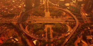 傍晚时分，印尼雅加达，新设的Semanggi高速公路交汇处的俯视图，有曲线桥和橙色的天空。拍摄分辨率为4k