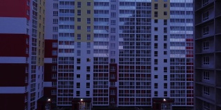 现代公寓建筑的彩色立面、窗户和阳台的无人机视图。航拍到高楼大厦的夜间画面。