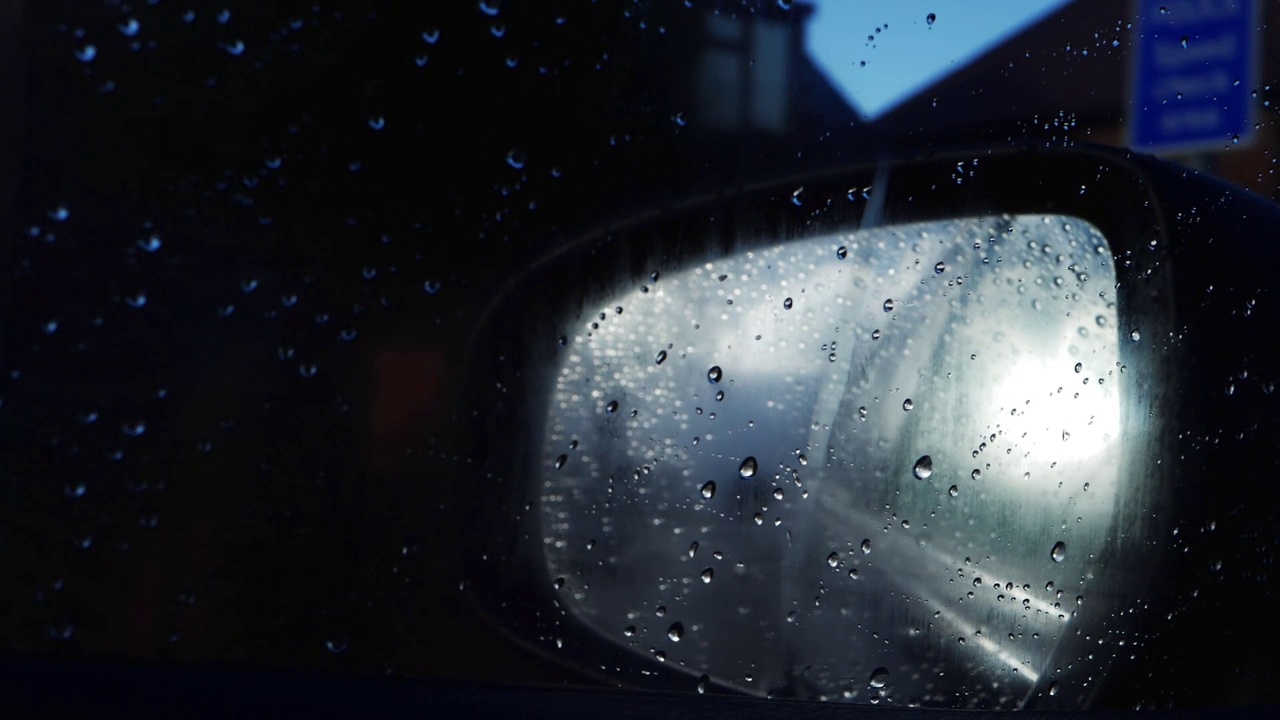 在雨中夜间驾车通过后视镜穿过市区