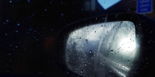 在雨中夜间驾车通过后视镜穿过市区