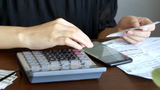 女人在线记账发票对账单与信用卡债务账单，使用计算器计算每月成本，税收，银行账户余额和费用财务在家里视频素材模板下载