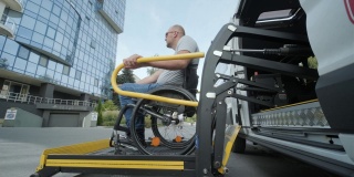 轮椅上的人坐轮椅的人，在残疾人专用车辆的升降机上残疾人的起重设备——在车辆附近坐轮椅的人