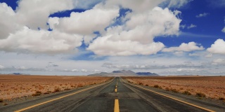 多云天空的半沙漠景观中的高速公路透视视图