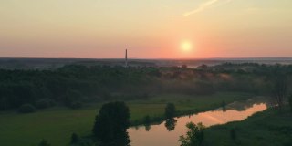 夏天的傍晚和日落在绿色的草地在乡村的河流-无人机拍摄