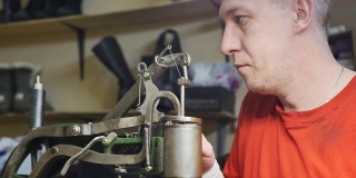 一个男鞋匠正在调整缝纫机，以便用结实的线缝鞋