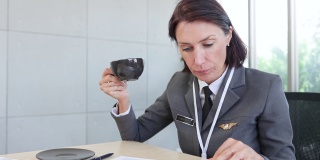 身着飞行员服的资深女商人坐在办公室的办公桌前检查报告。