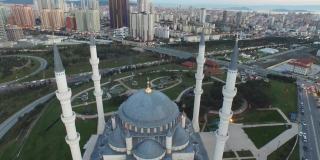 4k无人机电影观看照明夜景巨大的伊斯兰清真寺与拥挤的城市视图-现代和传统的伊斯兰建筑寺庙之间的摩天大楼和高速公路无人机拍摄包括近距离尖塔和圆顶-适合斋月和eid