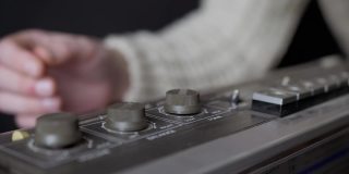 女性手指旋转音量，平衡旋钮在一台老式录音机。4K