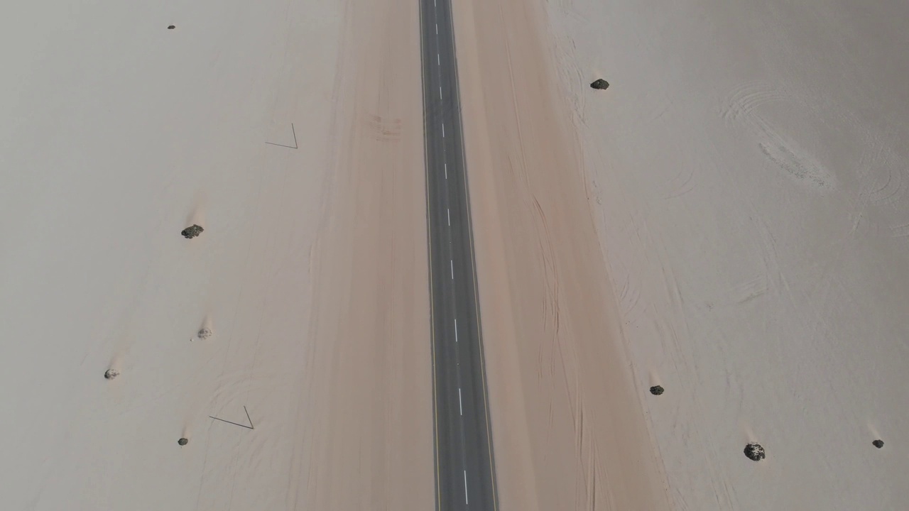高空无人机航拍的视频画面，这条永无止境的长而直的路通向非洲的纳米比亚。一辆白色货车沿着笔直的街道开到远处的地平线上。冒险徒步旅行roadtrip。