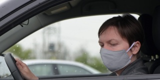 下雨天，一个带着防护面罩的忧心忡忡的女人在车里等着