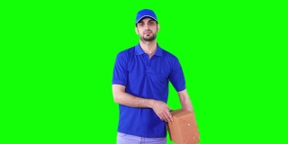 视频画面显示，一名年轻的快递员身穿蓝色制服，在绿色屏幕背景前递出一个盒子