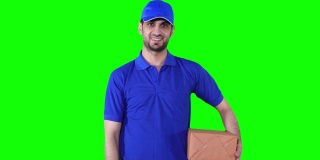 年轻男性快递员拿着一个包裹，在前面的绿色屏幕背景上竖起大拇指