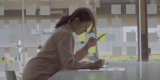亚洲女性使用智能手机做财务会计工作。