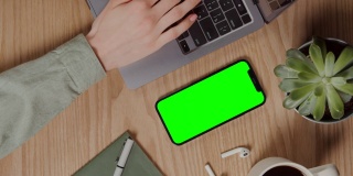 一台绿色屏幕的手机放在笔记本电脑旁边的台式机上