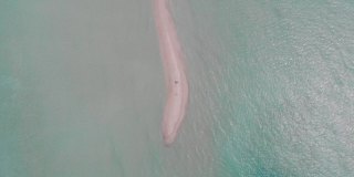 无人机在热带沙洲上空飞行，白种人夫妇绿松石和蓝色的水，珊瑚，一些船和白色的沙子。鸟瞰印度洋上风景如画的岛屿，马尔代夫，拉杜赫，阿利夫阿利夫环礁。
