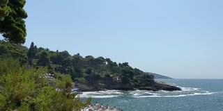 夏天的海滩海景。世外桃源般的海滩坐落在岩石嶙峋的地中海沿岸，四周是常绿的松树。放松的假期，在地中海度假。神奇的夏天海景。