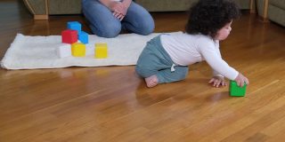 快乐的妈妈和宝宝在家里舒适的地毯上玩小方块，