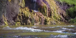 令人惊叹的无人机特写镜头，热气腾腾的水从岩石顶部流动