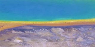 无人机视图彩虹湖边缘与梯度彩色海岸线，流光黄色温跃层细菌，清澈的蓝色水陆地外观。