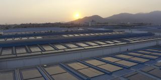 日落时分，安装在大型工厂屋顶上的太阳能电池板的航拍照片
