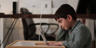 学龄前儿童正在通过平板电脑或玩电脑游戏进行远程学习