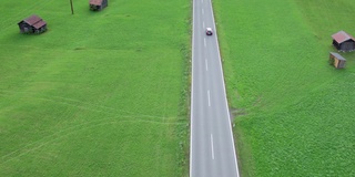 在奥地利的绿色田野之间的道路在一个高山村庄，鸟瞰图