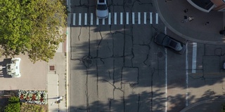 空中的俯仰无人机视图的行人在道路上的交叉。汽车在城市街道上行驶。伊利诺斯州内伯维尔大街上的许多家庭。