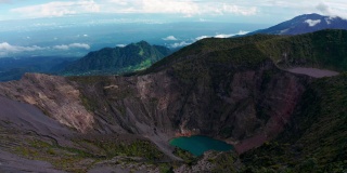 在哥斯达黎加的伊拉苏火山国家公园风景优美的自然，有蓝色的水火山口湖和郁郁葱葱、充满活力的绿色热带雨林山丘在远处的地平线上。空中无人机鸟瞰火山景观。