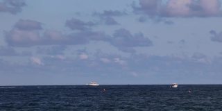 在南佛罗里达劳德代尔堡海滩附近的地平线上，各种各样的休闲船和水射流穿过框架和静止的航运船的海洋海岸场景