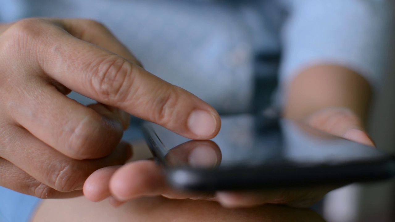 近距离观察一名女子的手指，她正在移动应用程序上滚动智能手机触摸屏上的在线购物项目。