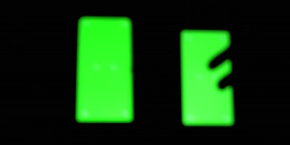 在暗室里，智能手机的绿色屏幕上滑过一只手的黑色剪影