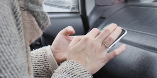 穿着外套的女人的手用手指按在智能手机上