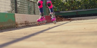 近距离的腿骑在旱冰鞋。女孩开着旱冰鞋。街头运动的概念。轮滑培训。
