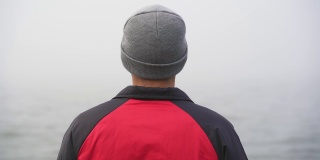 慢动作中景拍摄男性在雾中行走在木制码头上的海洋