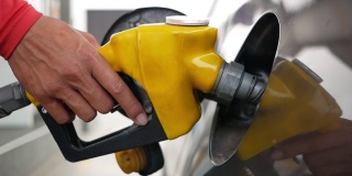 汽车在加油站加油。在加油站，男性员工用加油喷嘴控制加油泵向汽车中添加汽油。