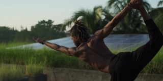 男子在屋顶太阳能电池上做站立弓高温瑜伽姿势快速慢动作