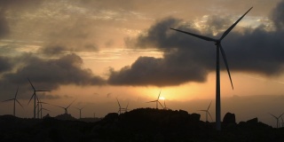 在福建省莆田市沿海的山上，一排晚霞和风力涡轮机在天空中旋转