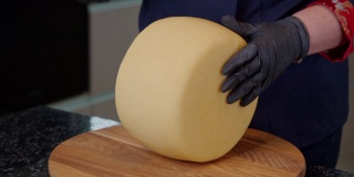 一名奶酪奶场工人正在检查煮熟的硬奶酪。销售前对产品质量进行评估。