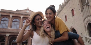 三个女人背对着摄像机的肖像。女孩们站在一个旅游城市的广场上。