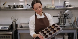 一位女糕点师在厨房里拿着制作果仁巧克力的表格。